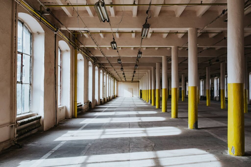 Interior of an abandoned building hall with yellow pillars Stock Free