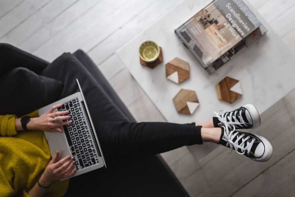 Young woman sitting on the sofa and working on her laptop Stock Free