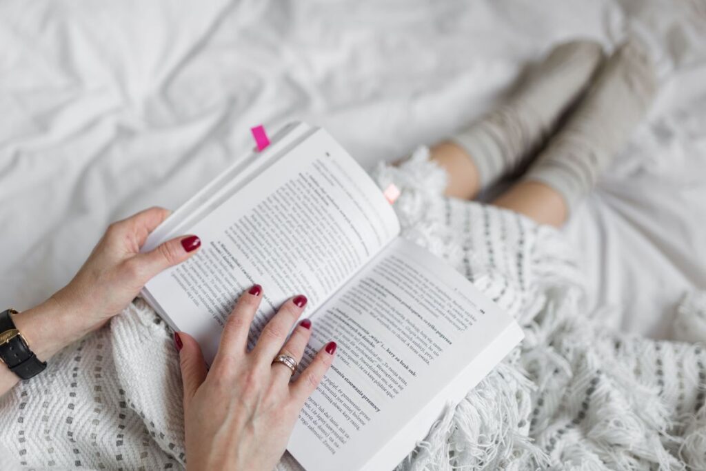 Soft photo of woman on the bed with the book and cup of coffee in hands Stock Free