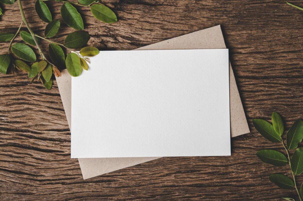 A blank card is placed on envelope and leaf with wood background Stock Free