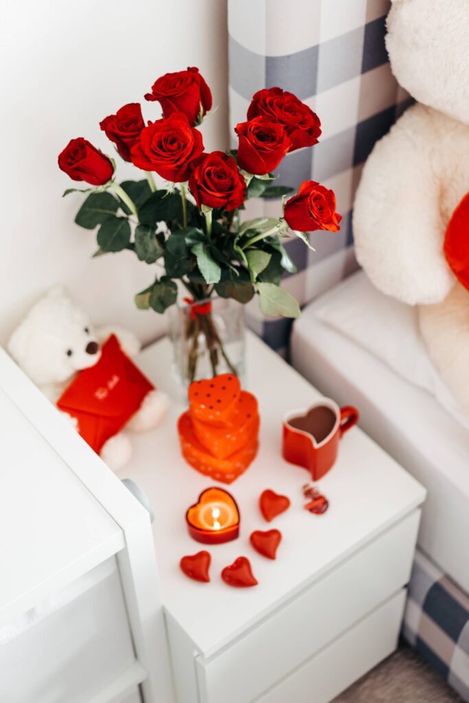 A Bouquet of Red Roses And Other Romantic Gifts on a Bedside Table Free Photo