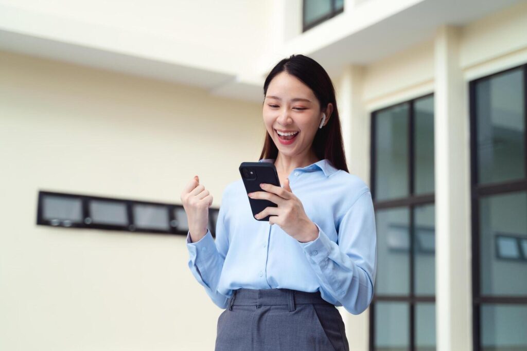 A business woman is smiling and holding a cell phone. She is happy cheerful Stock Free