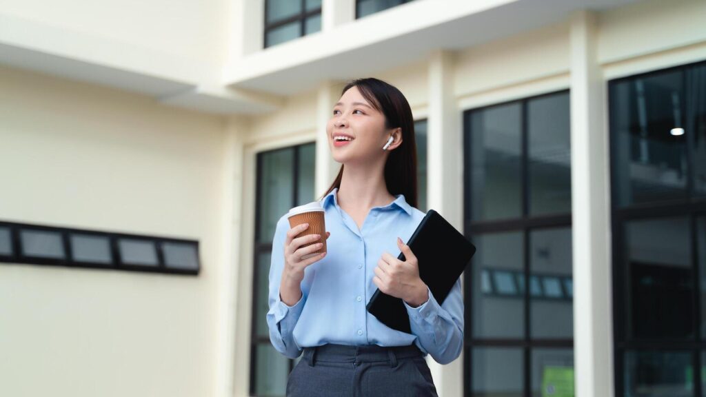 A business woman is standing in the city with a cup of coffee and a tablet Stock Free