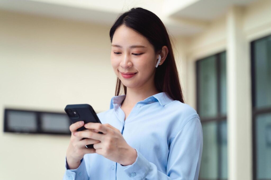 A business woman is using the smart phone while standing outside Stock Free