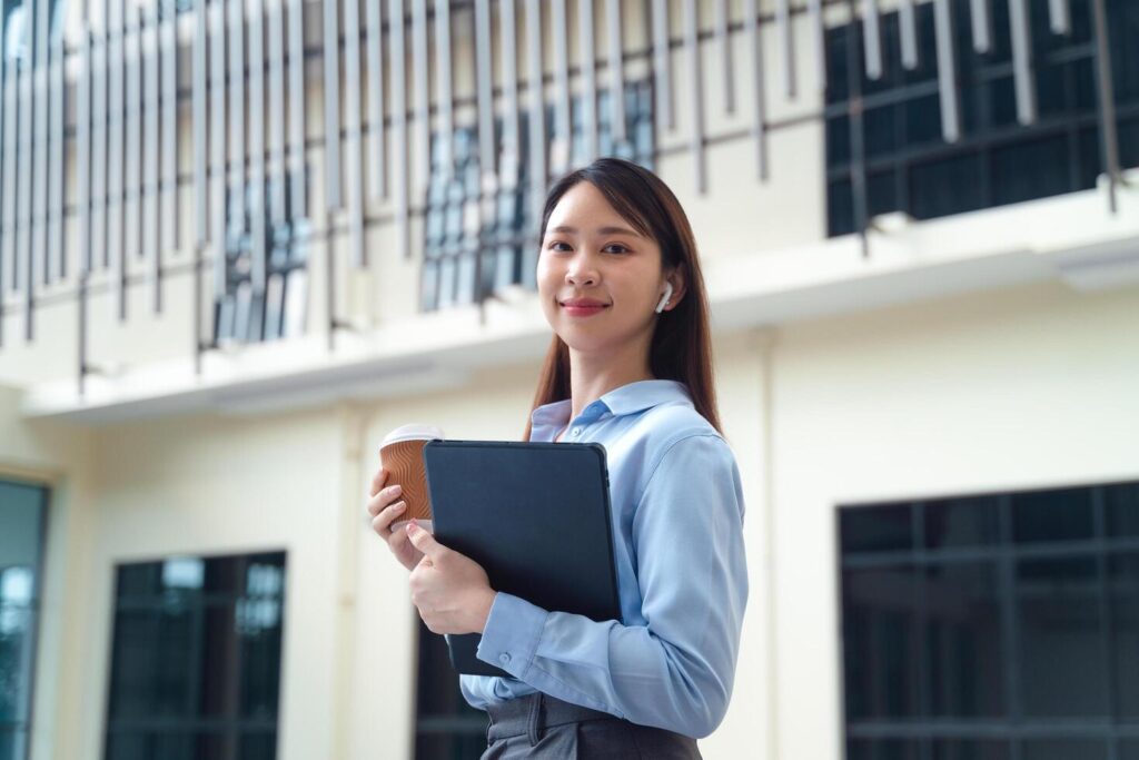 A business woman wearing a blue shirt and holding a cup of coffee and a tablet Stock Free