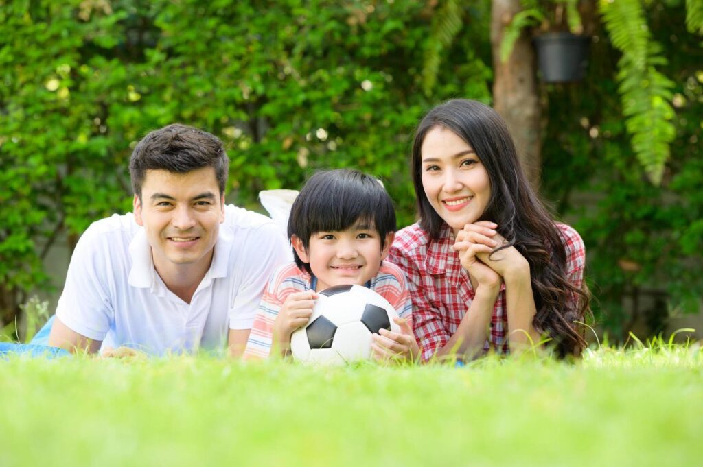 A happy young family spends time playing together in the garden at the front of house the vacation. Stock Free