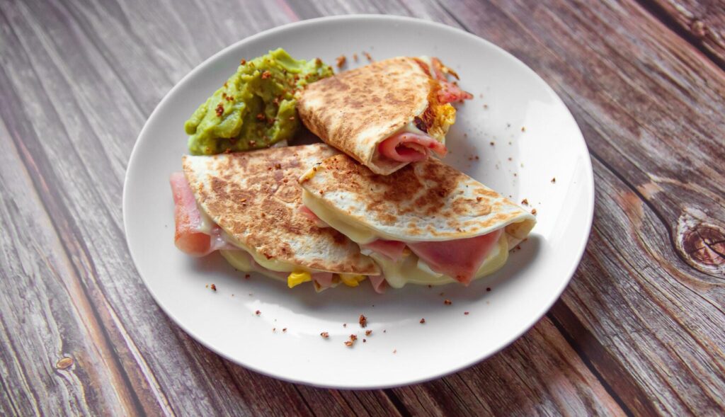 A plate of food with a quesadilla and guacamole on it. Stock Free