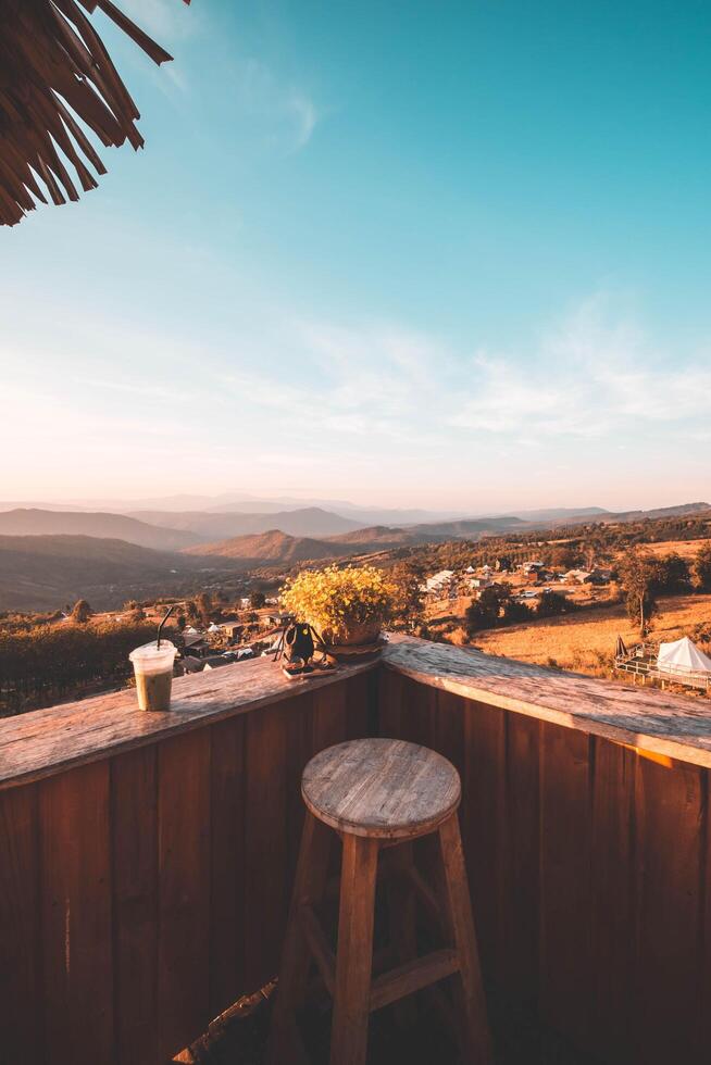 A view of the hill from the coffee shop, including a sunset in the background and a wooden chair placed into a corner. Stock Free