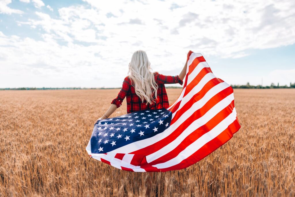 A Woman Walking in a Field with The American Flag Free Photo