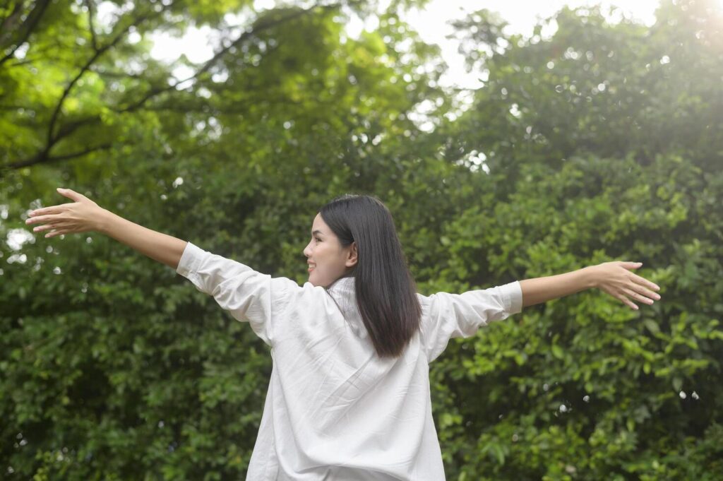 A young healthy woman smiling , refreshing in nature background Stock Free