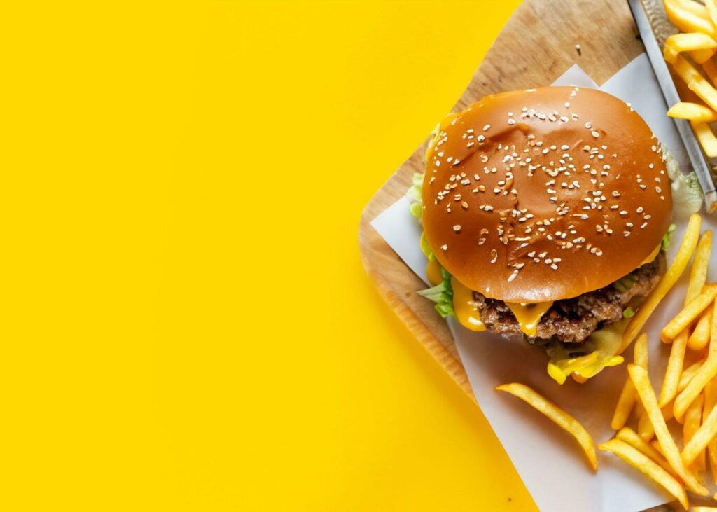 AI Generated burger and french fries with yellow background Stock Free