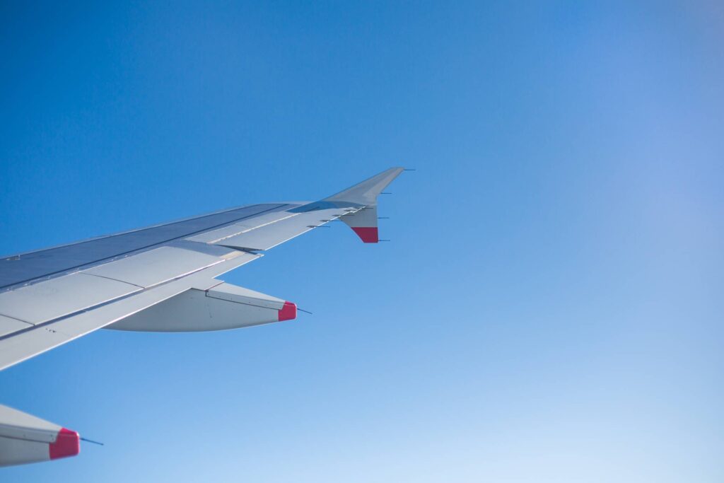 Airplane Wing and Bright Sky Through an Airplane Window Free Photo