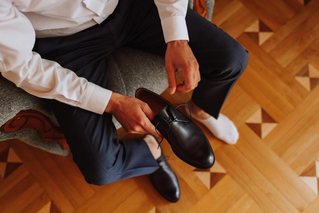 An elegant man wears black leather formal shoes. Tying shoes. Business man tying shoelaces on the floor. Up close The groom is preparing for the wedding. Stock Free