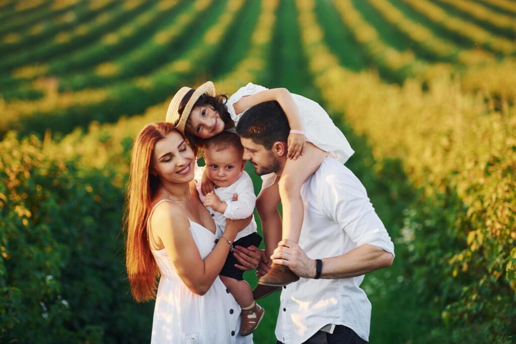 At agricultural field. Father, mother with daughter and son spending free time outdoors at sunny day time of summer Stock Free