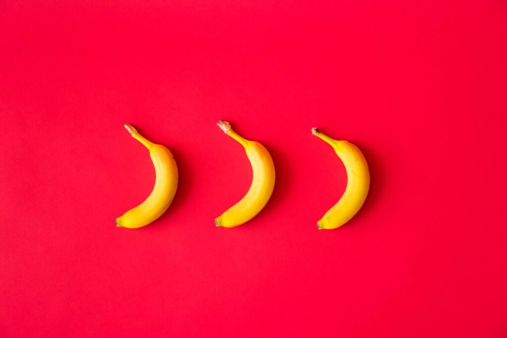 Bananas with Red Flat Background Free Photo