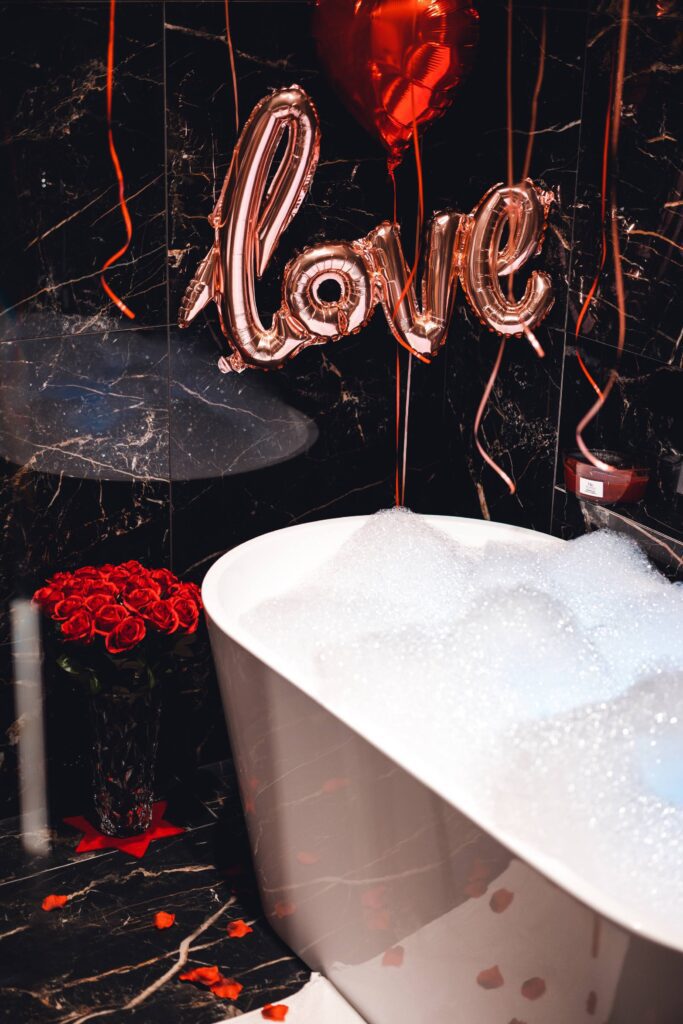 Bathtub Full of Foam in Luxury Bathroom with Roses and Love Balloon Free Photo