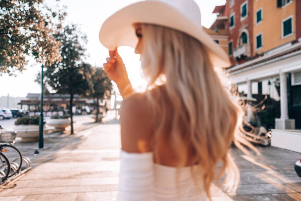 Beautiful Blonde Woman in White Straw Hat Walking Around Rovinj, Croatia Free Photo