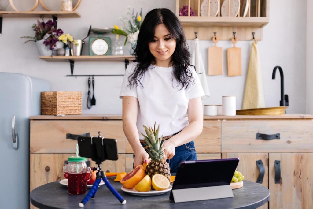 Beautiful girl prepares delicious healthy food and shoots video for her blog Stock Free