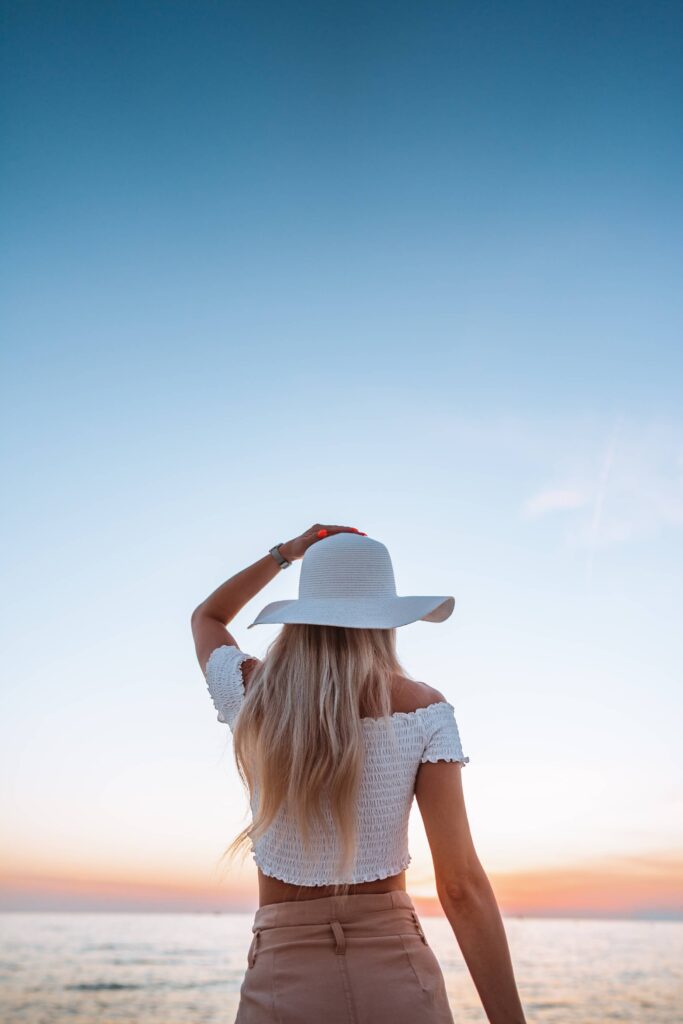 Beautiful Woman in a Hat Enjoying Sunset by the Sea Free Photo