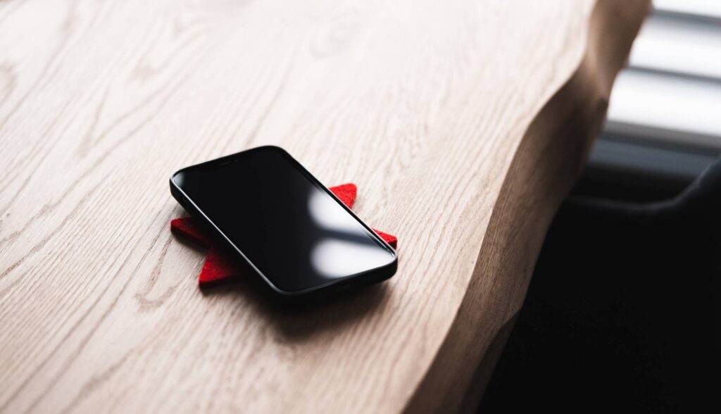 Black Smartphone Lying on a Wooden Table Free Photo