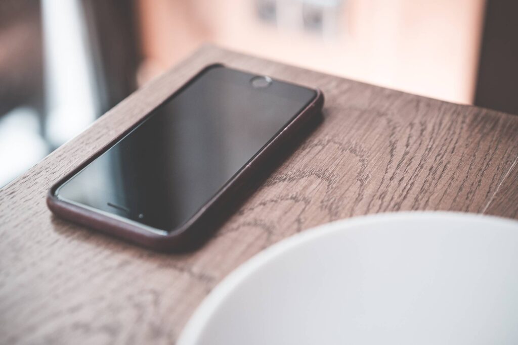 Black Smartphone on Wooden Table in Café Free Photo