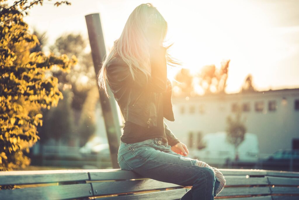 Blonde Woman Sitting Alone on a Bench Against Sunset Free Photo