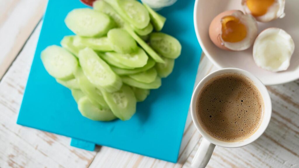 Boiled eggs with fresh cucumber salad and coffee cup breakfast set – top view breakfast food concept Stock Free