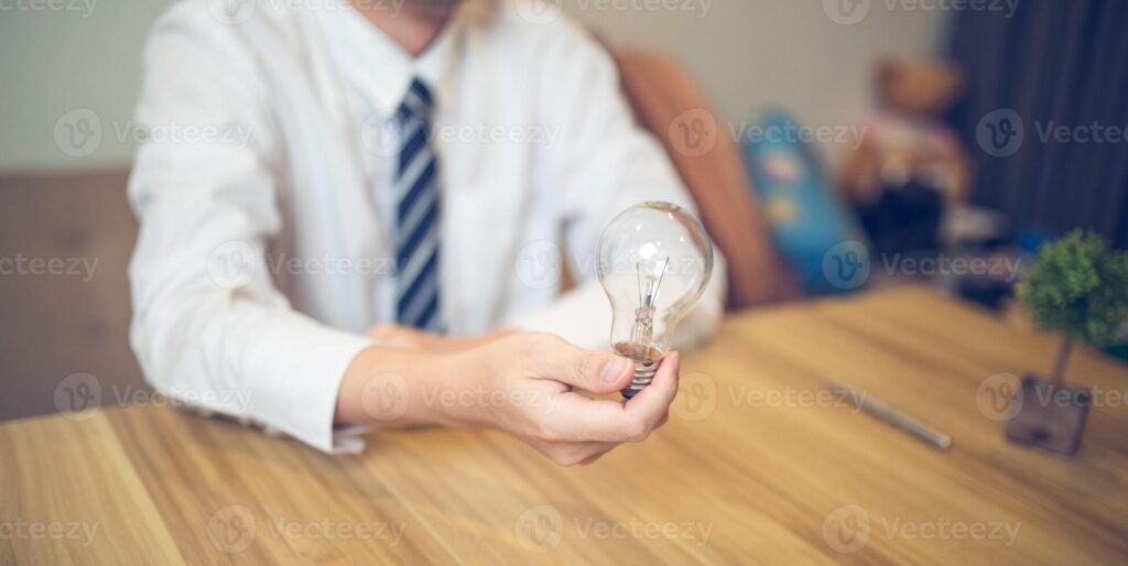 Business professional holding a light bulb in a creative brainstorming session, symbolizing ideas and innovation Pro Photo