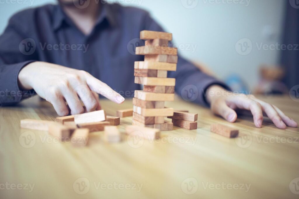 Business strategy concept with hands playing a wooden block tower game, symbolizing risk and stability. Planning risk management Pro Photo