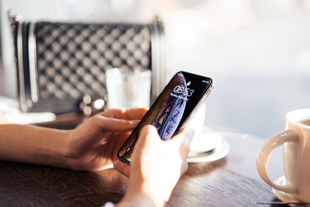 Business Woman Using Her iPhone in a City Café Free Photo