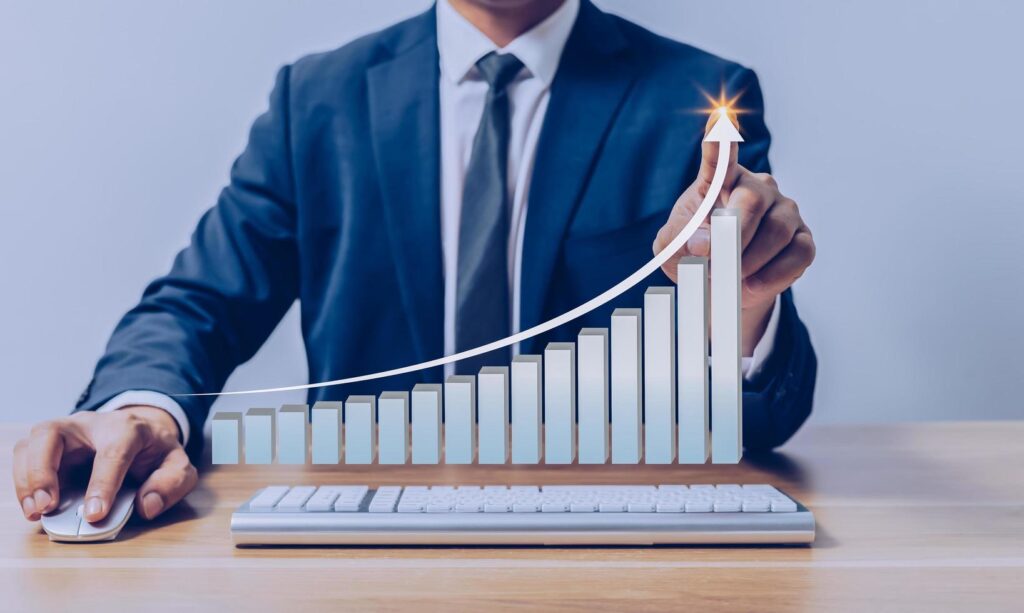 Businessman pointing to virtual investment bar and line graph on wooden table as business strategy and stock value investor concept. Stock Free