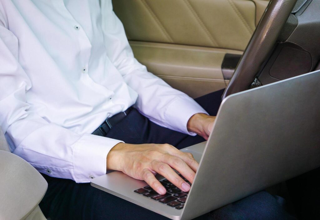 Businessman working on laptop while sitting on driver seat in car. Lifestyle concept. Stock Free