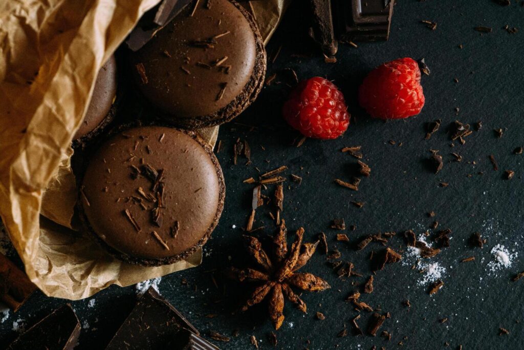 chocolate macarons with raspberries on a dark background Stock Free