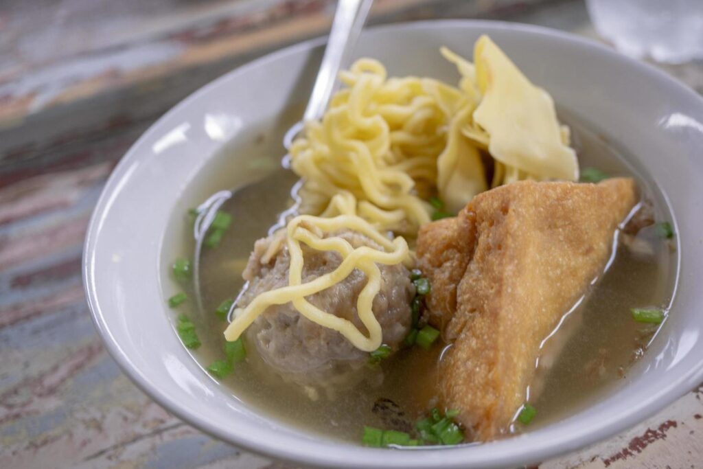 Close up photo of Bakso, traditional meatball of Malang Indonesia, with noodles and tofu. The photo is suitable to use for traditional food background, traditional food poster and food content media. Stock Free