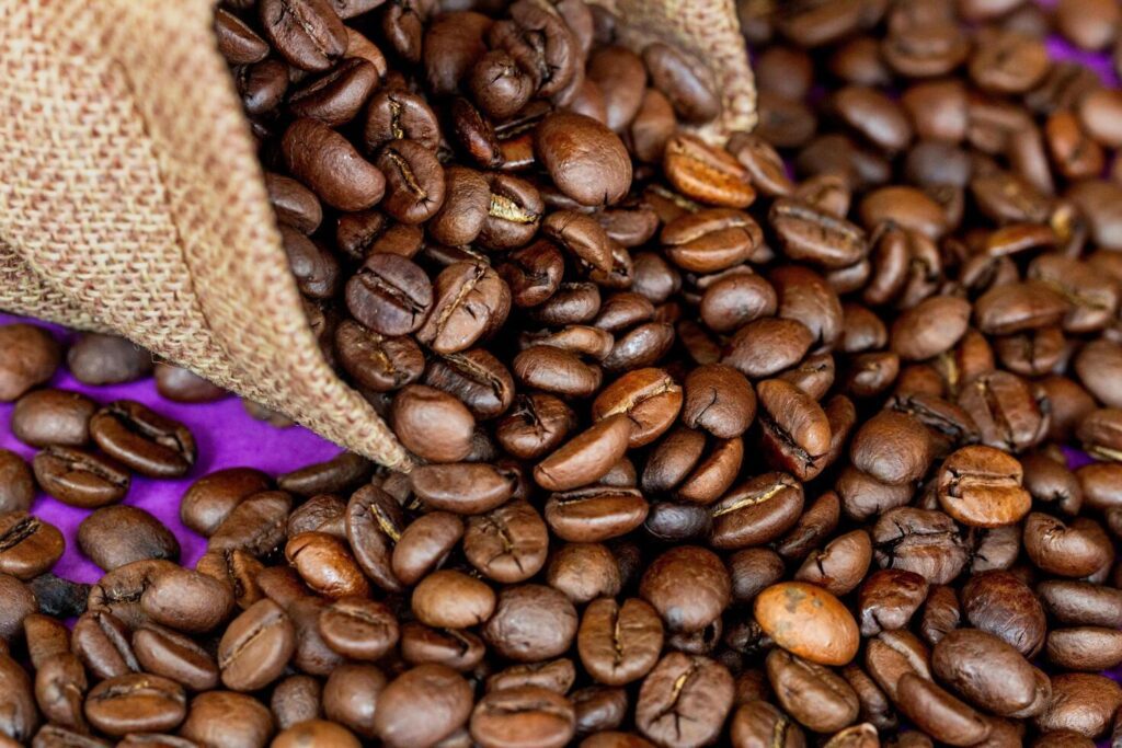 coffee beans in a burlap bag on the purple background Stock Free