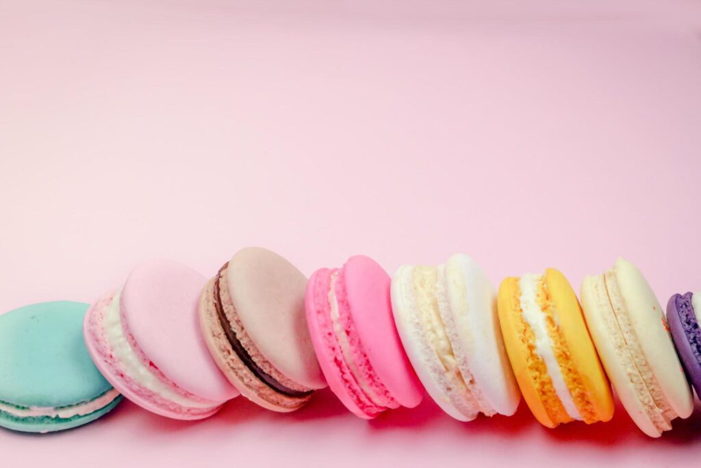 Colorful french macarons macaroons cake, delicious sweet dessert on a pink background with copyspace, food background concept. Free Photo