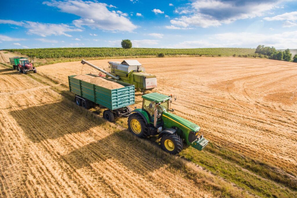 Combine Harvester Pouring Grain into Trailer Towed by Tractor Free Photo