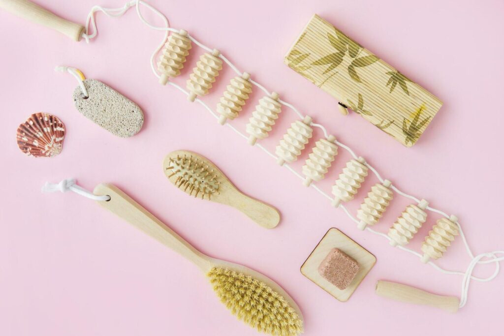 Concept of Spa-cosmetic and cosmetic procedures. Spa-sea salt, wooden comb, massager, anti-cellulite massage brush on a pink background. The concept of a waste-free lifestyle. Stock Free