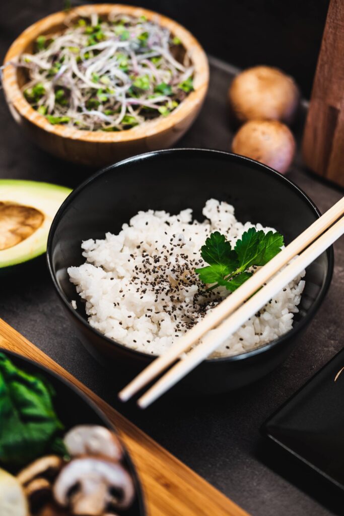 Cooked Jasmine Rice in a Dark Bowl with Chopsticks Free Photo