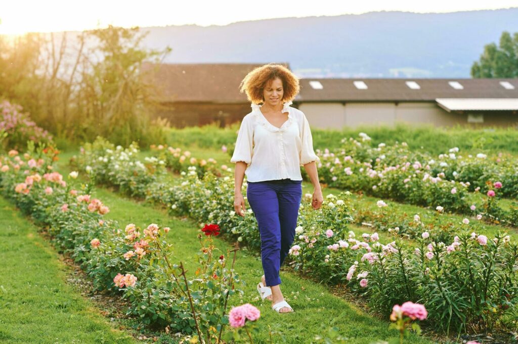 Countryside lifestyle, outdoor portrait of beautiful middle age 50 – 55 year old woman enjoying nice day in flower farm garden Stock Free