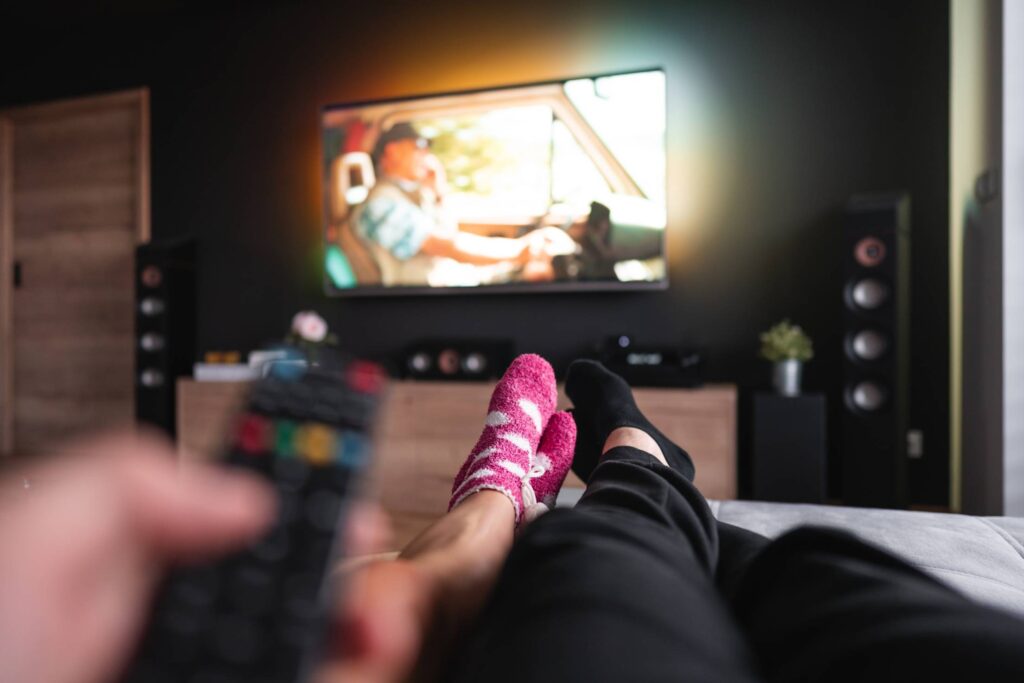 Couple Lying on a Sofa and Watching Movies Free Photo