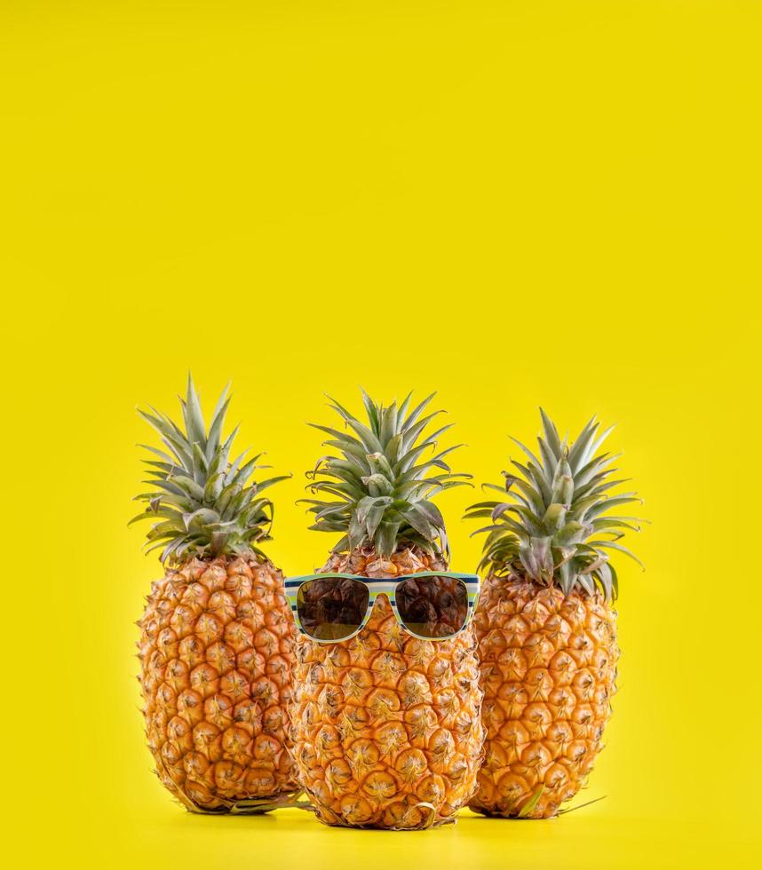 Creative pineapples with sunglasses isolated on yellow background, summer vacation beach idea design pattern, copy space, close up, blank for text Stock Free