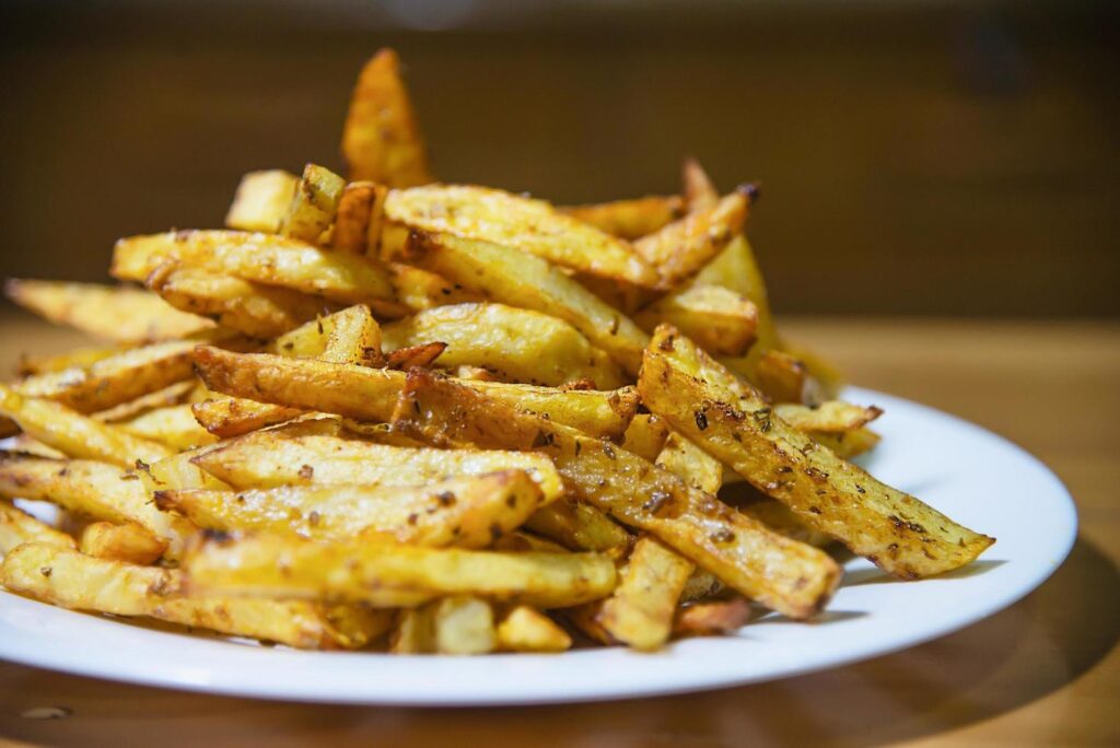 Delicious French fried potato mix with chilly powder on wooden table – traditional fast food concept Stock Free