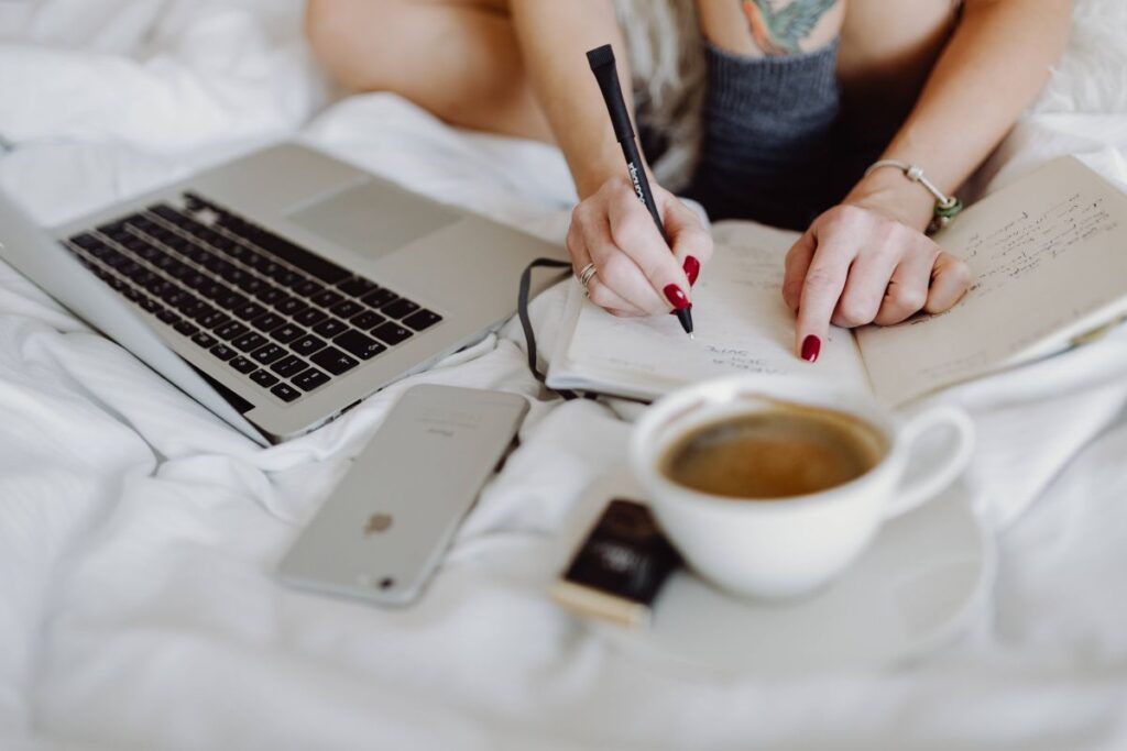 Woman working on a laptop while enjoying a breakfast coffee and chocolate in bed Stock Free