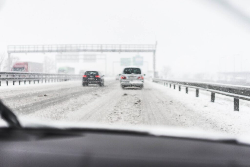 Driving in a Dangerous Snowy Weather on a Highway (focus on snowflakes) Free Photo