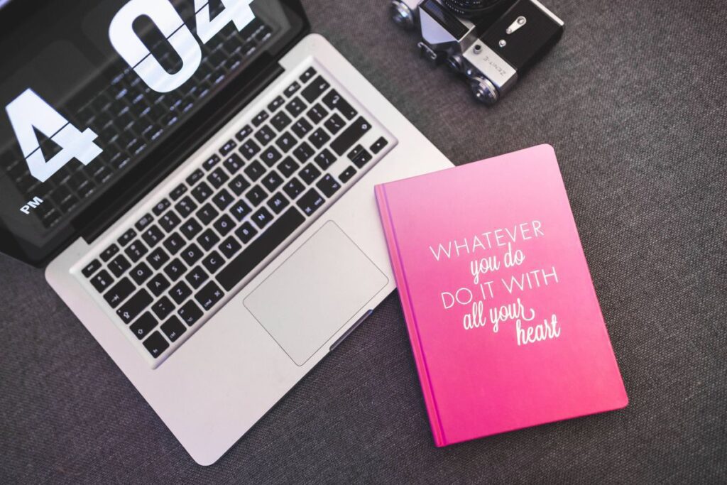 Pink notebook with a silver laptop and a camera Stock Free