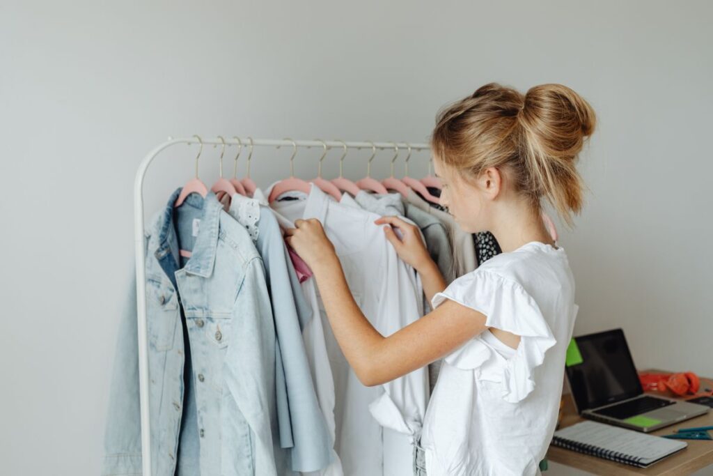 A teenager picks clothes from a hanger in her room Stock Free