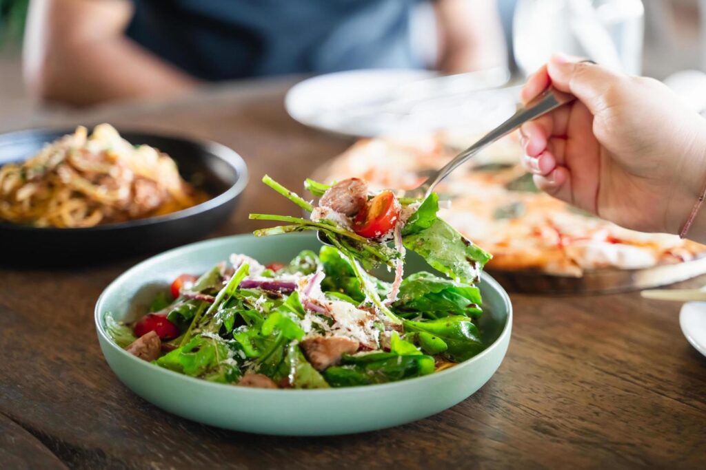 Eating salad. people eating Italian food Pasta, Pizza, Salad on the table. Stock Free