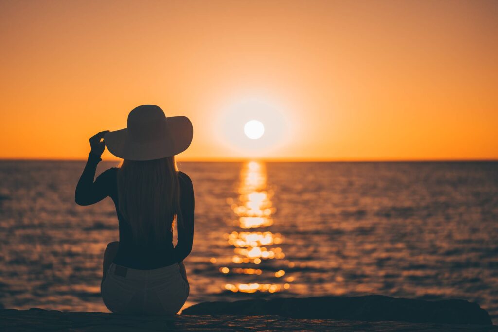 Elegant Woman Sitting on the Shore and Enjoying Sunset Free Photo