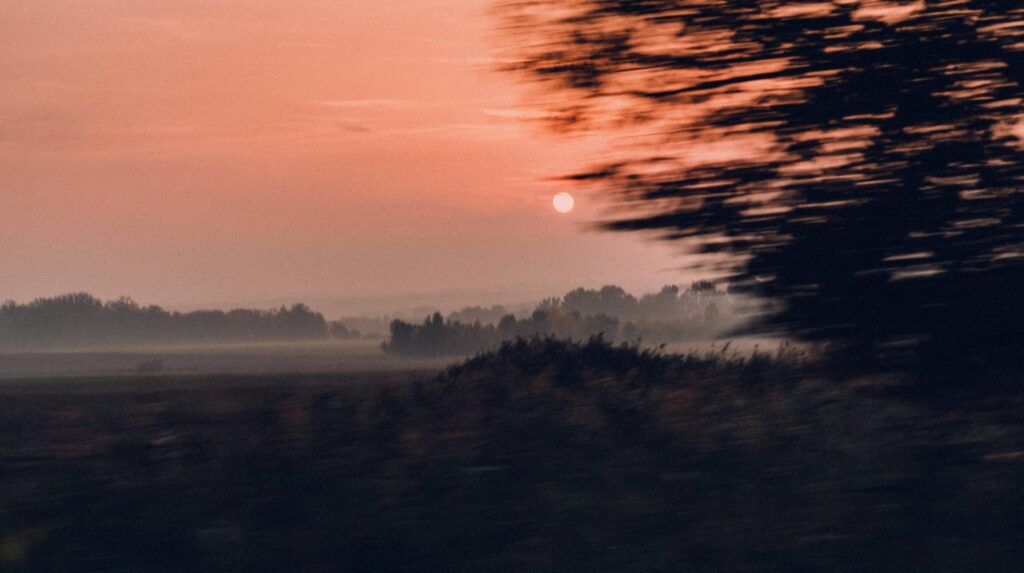 Evening Red Sun Just Above Horizon Landscape from Moving Car Free Photo